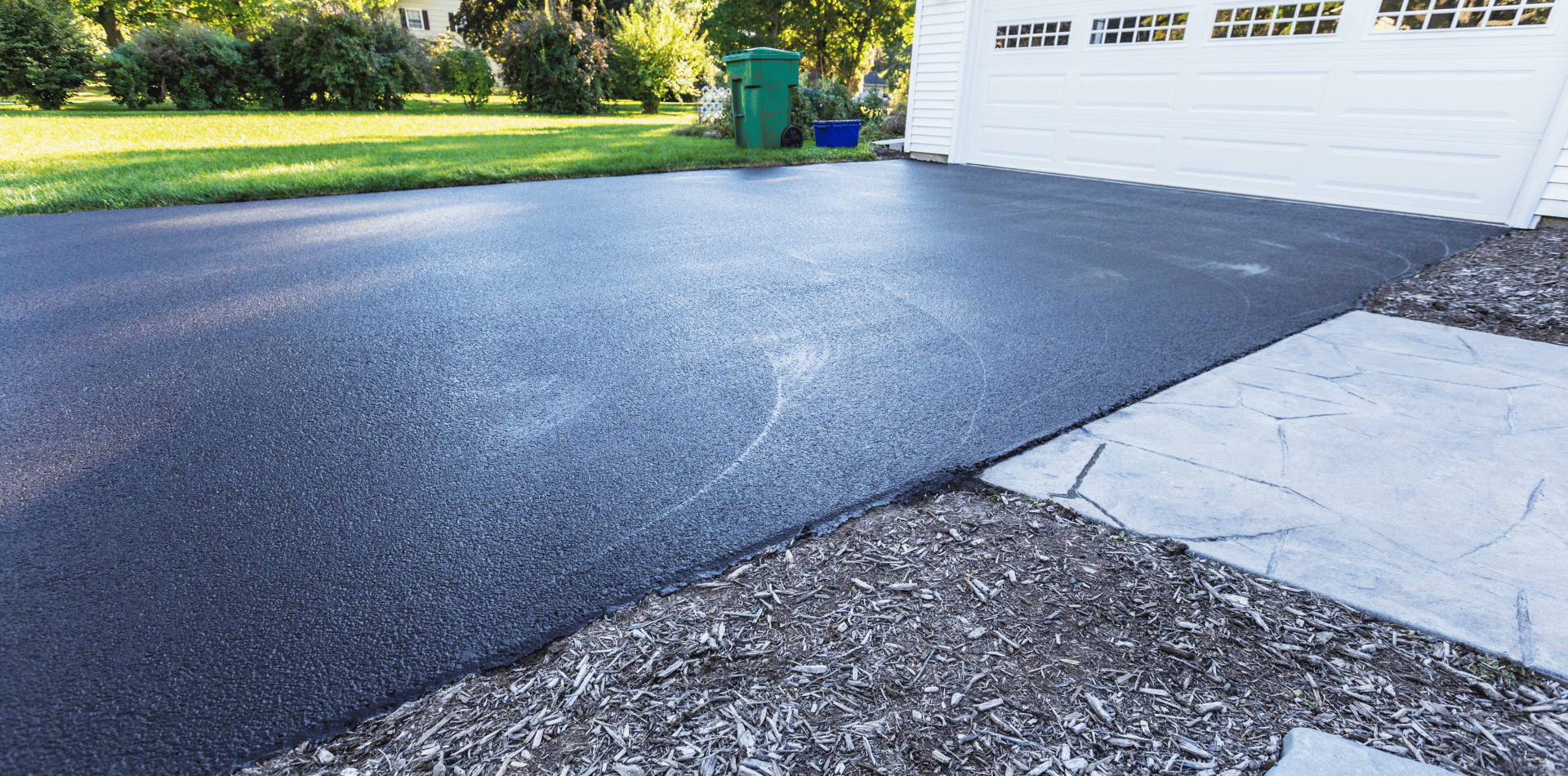 A black asphalt driveway next to a white garage door.