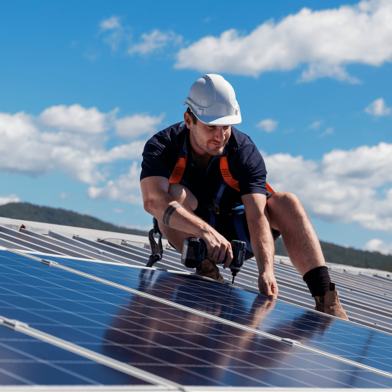A man wearing a hard hat is working on a solar panel