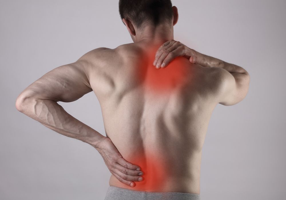 Man with back pain, indicated by red highlighting on shoulder, back, and lower back, holding his neck and lower back.