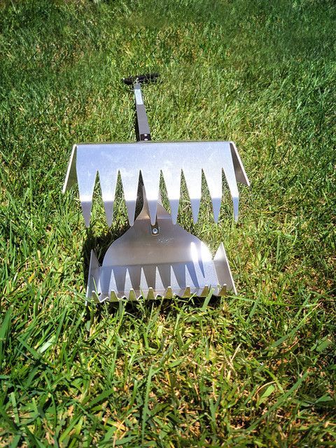 A stainless steel rake and shovel are sitting in the grass