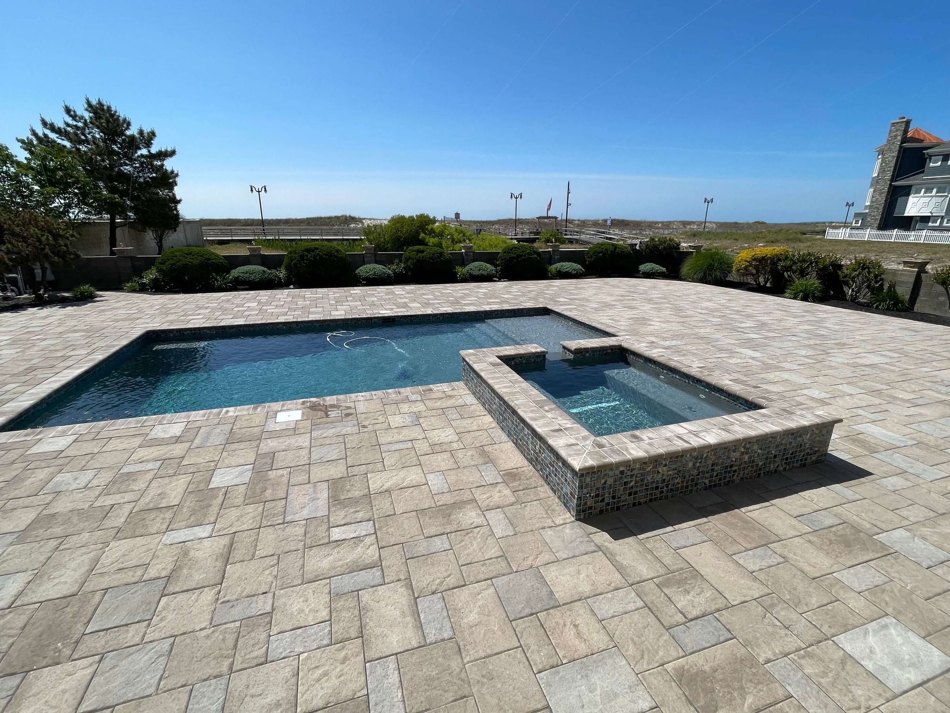 Stone patio with a small swimming pool and hot tub overlooking the ocean