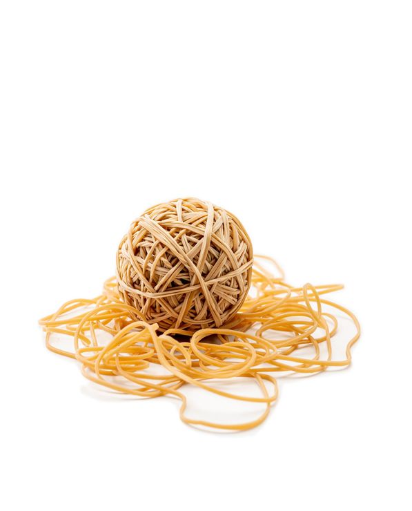 Palla fatta di elastici intrecciati, appoggiata su un mucchio sparso di elastici color marrone chiaro.