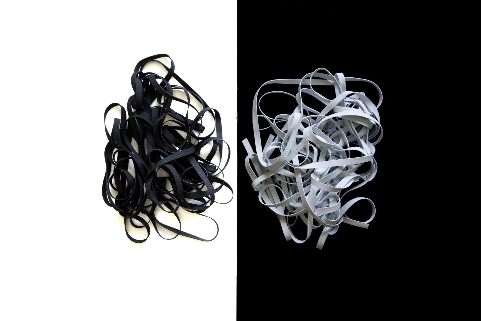 Nastri aggrovigliati bianchi e neri su lati opposti di uno sfondo diviso in bianco e nero.