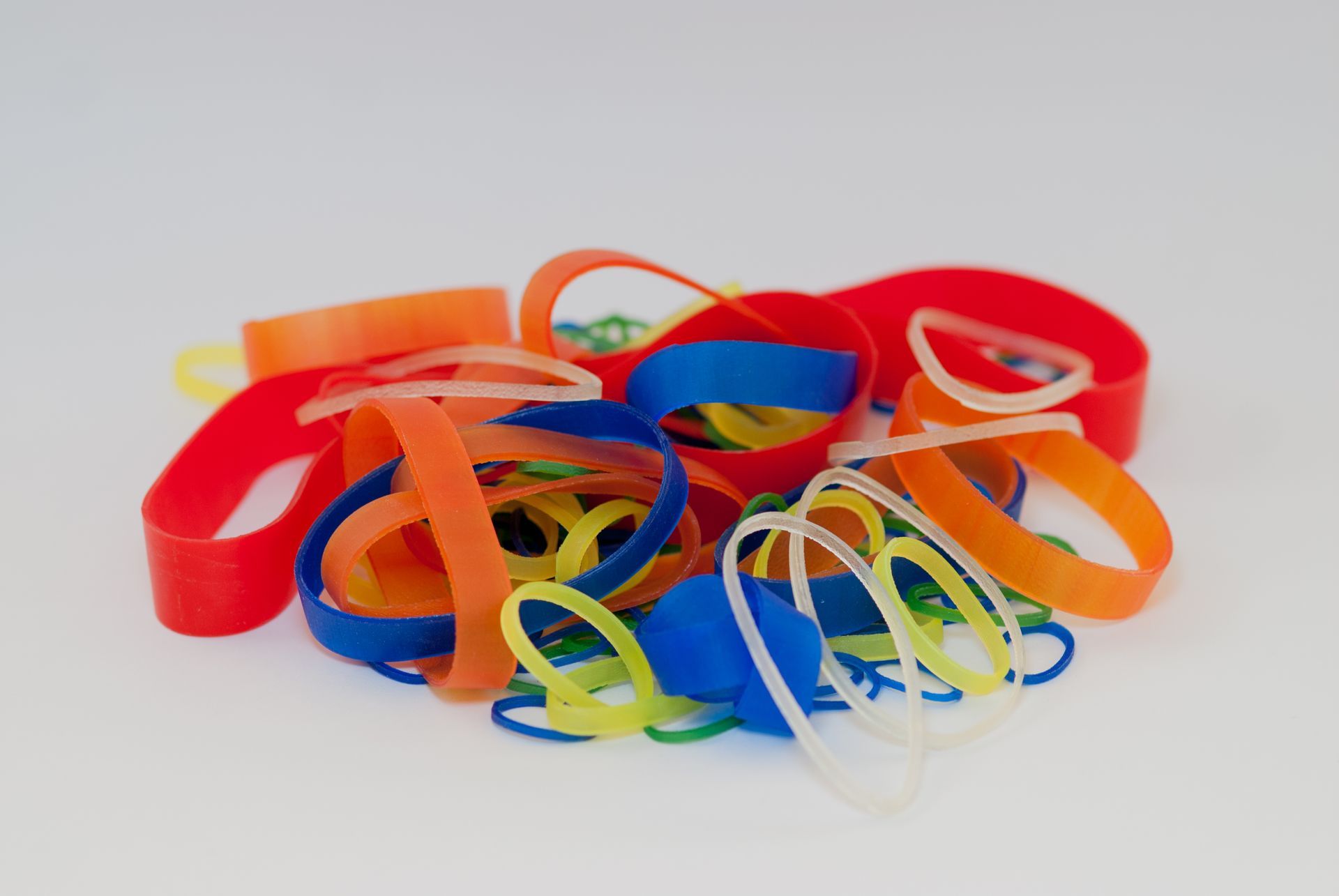 Mucchio di elastici colorati: rosso, arancione, blu, verde e trasparente.