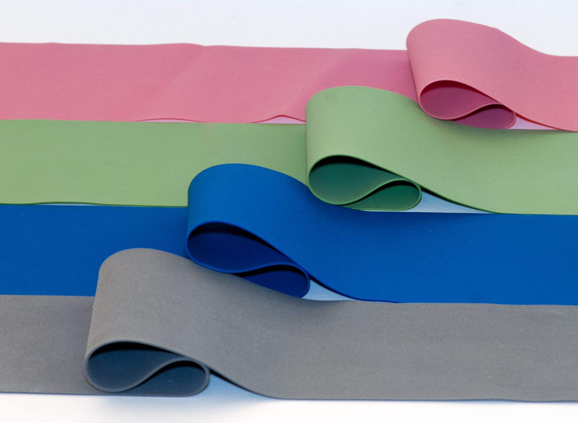 Fasce elastiche colorate per esercizi stese su uno sfondo bianco.