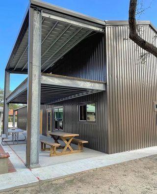 A metal building with a picnic table and benches underneath it.