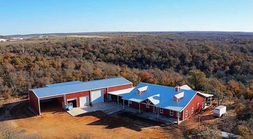 An aerial view of a large red barn surrounded by trees.