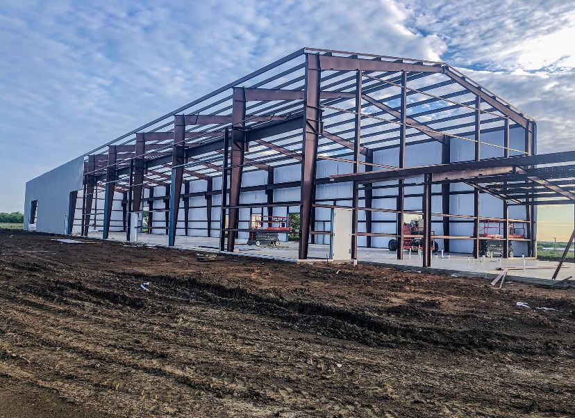 A large building is being built in the middle of a dirt field.