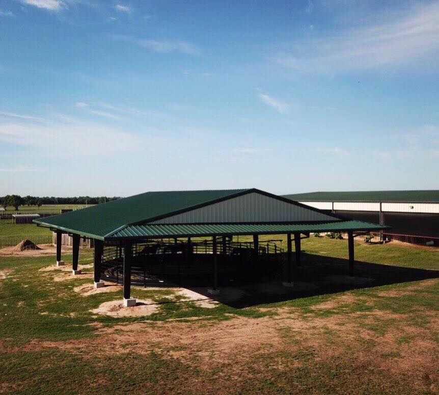 An aerial view of a pavilion with a green roof in a field.