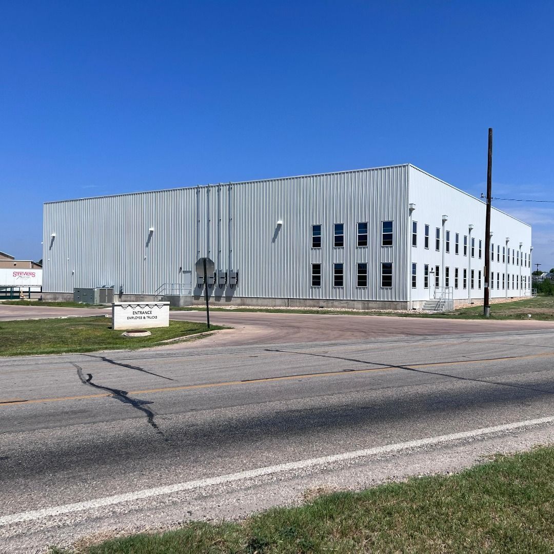 A large white building is sitting on the side of a road.