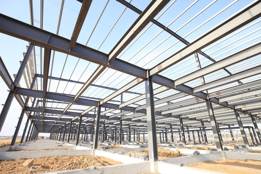 A large metal structure is under construction with a blue sky in the background.