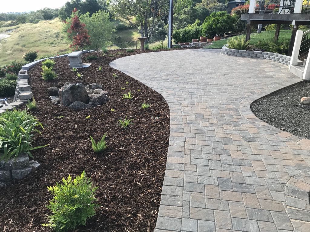 Stone patio with garden bed and hillside view.