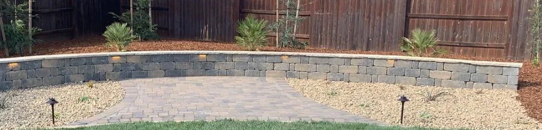 Courtyard with rock garden; gray stones, brown mulch, and two brick pillars.