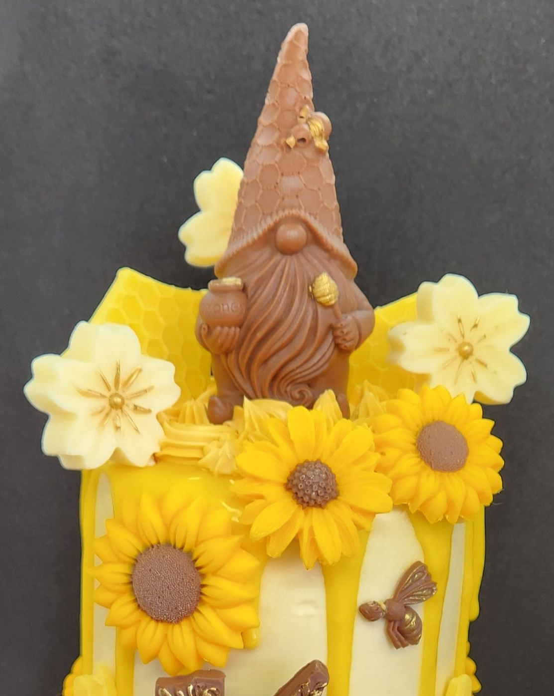 Cake decorated with sunflowers, a chocolate gnome, honey, and bees.