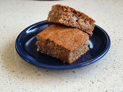 Two square brown baked goods on a blue plate, set on a light-colored countertop.