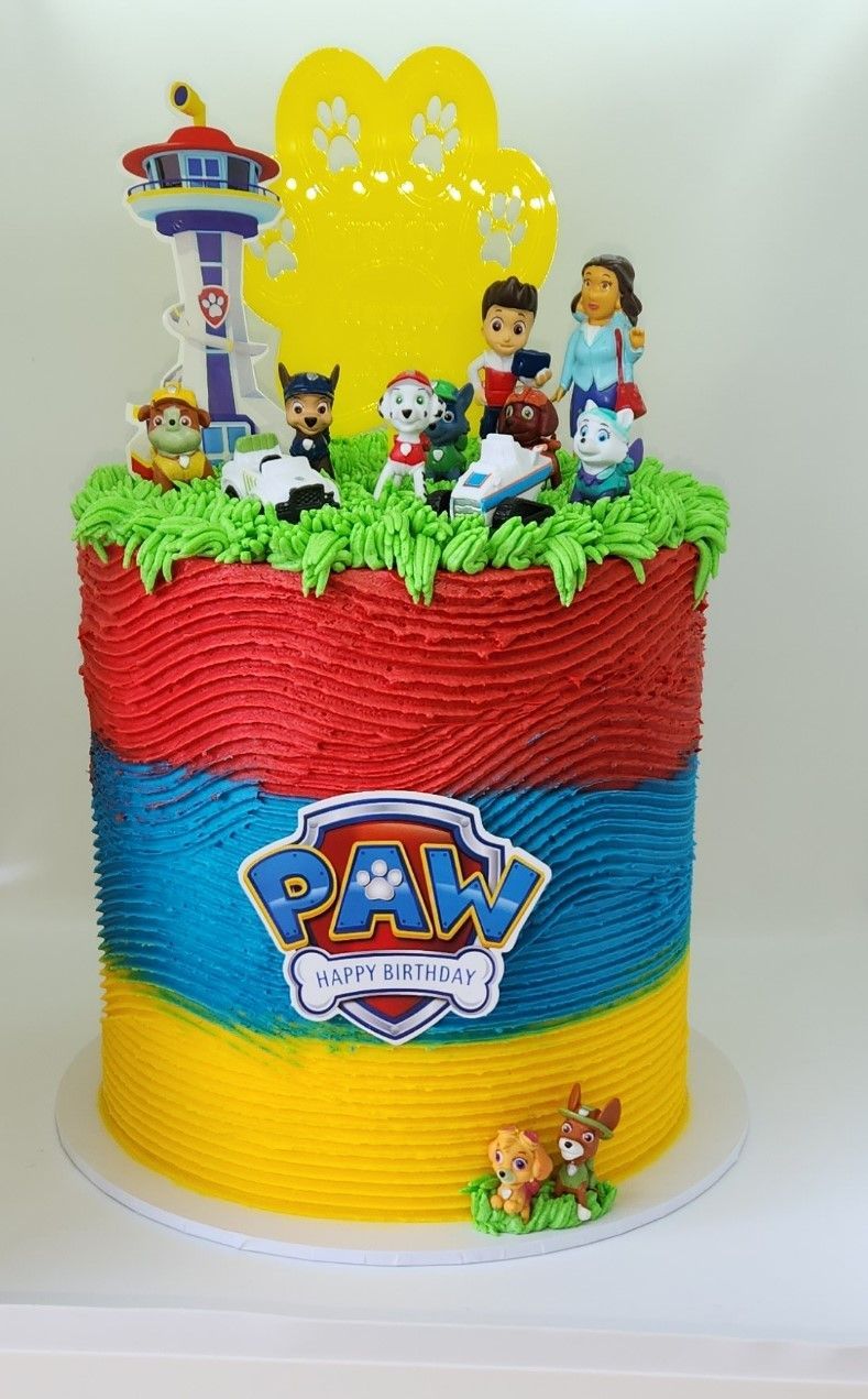 Paw Patrol themed cake with figurines and colorful frosting layers.