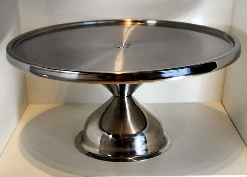 Stainless steel cake stand with a round, raised surface.