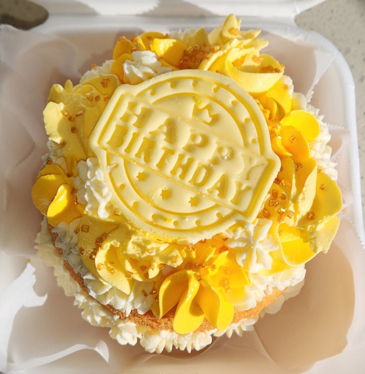 Yellow and white frosted birthday cupcake with a 