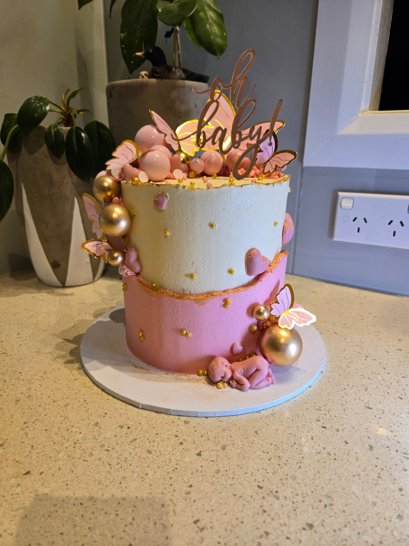  Baby shower cake with pink and white frosting, gold accents, and a 