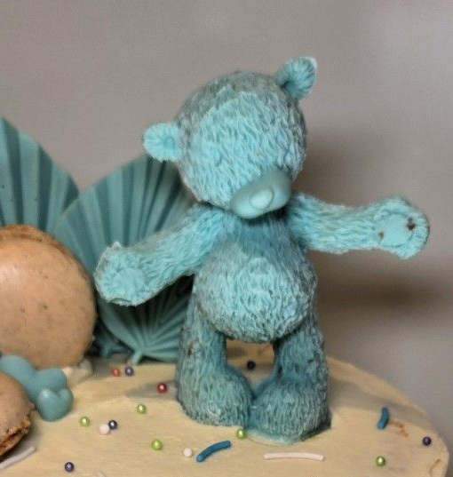 Blue teddy bear cake topper with outstretched arms.