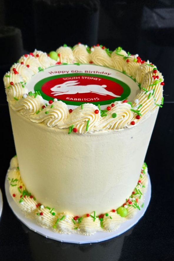 Anniversary cake with green leaf design, two blue birds, and gold 