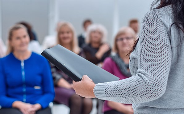 A woman is holding a folder in front of a group of people.