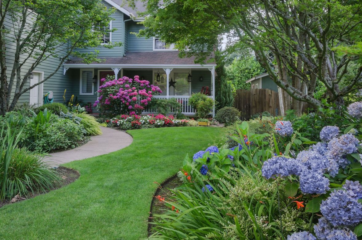 A house with a lush green lawn and flowers in front of it.