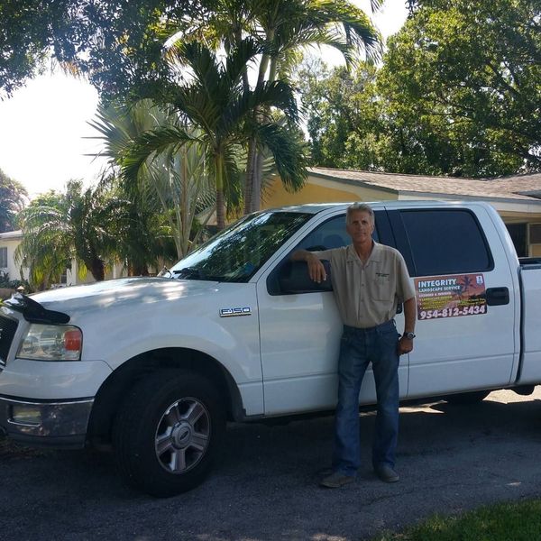 A man is standing in front of a white truck that says lawn service