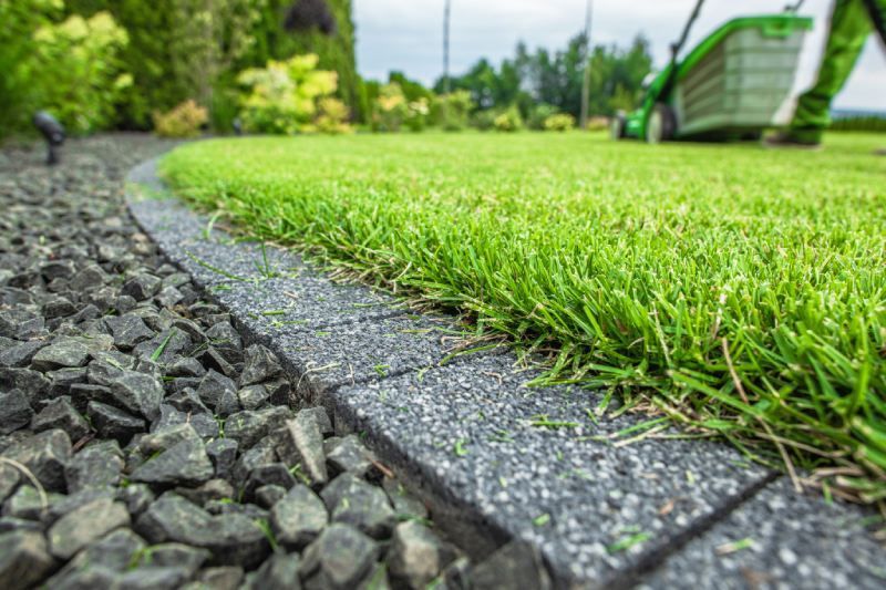 A green lawn mower is cutting a lush green lawn.