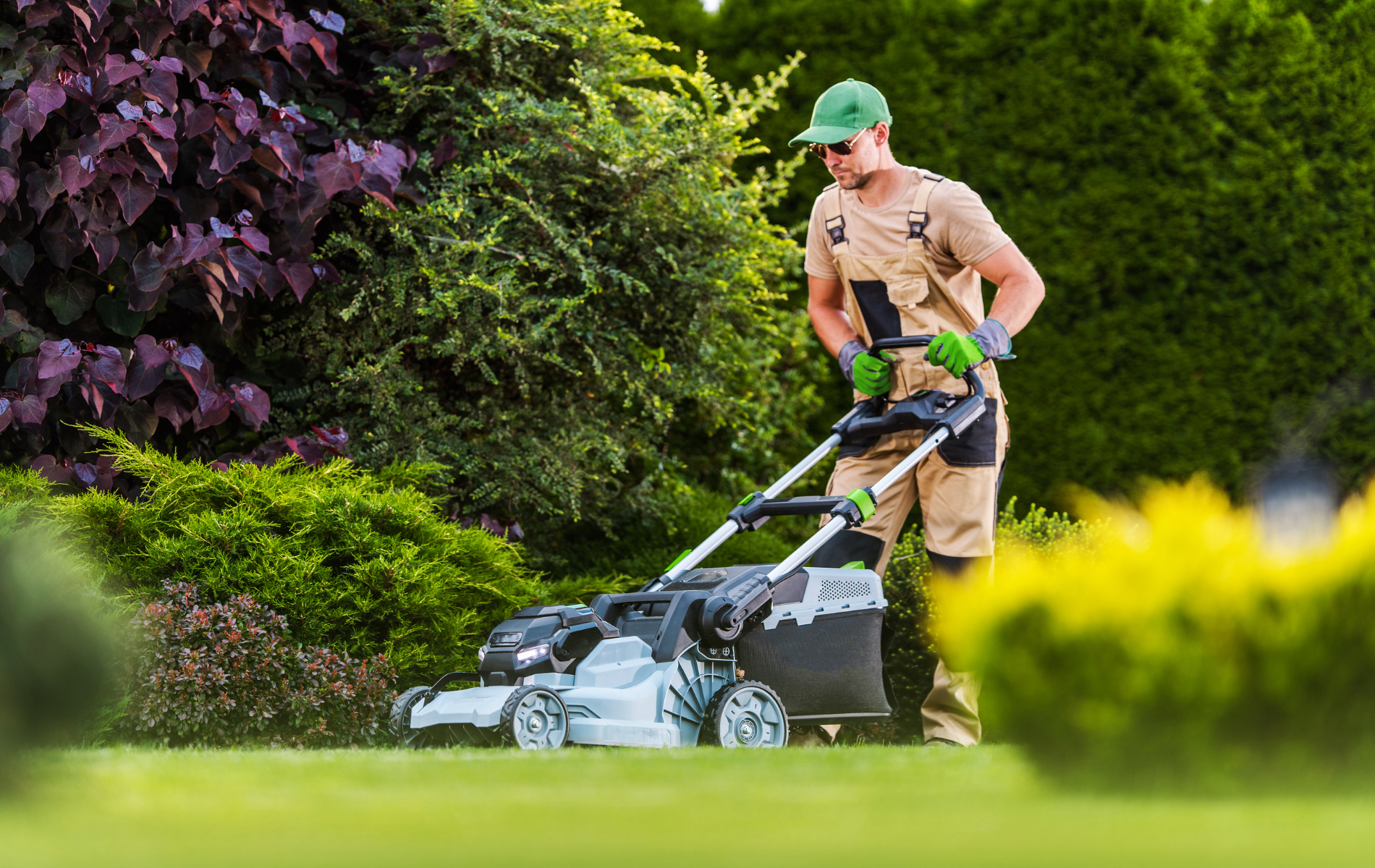A man is mowing a lush green lawn with a lawn mower.