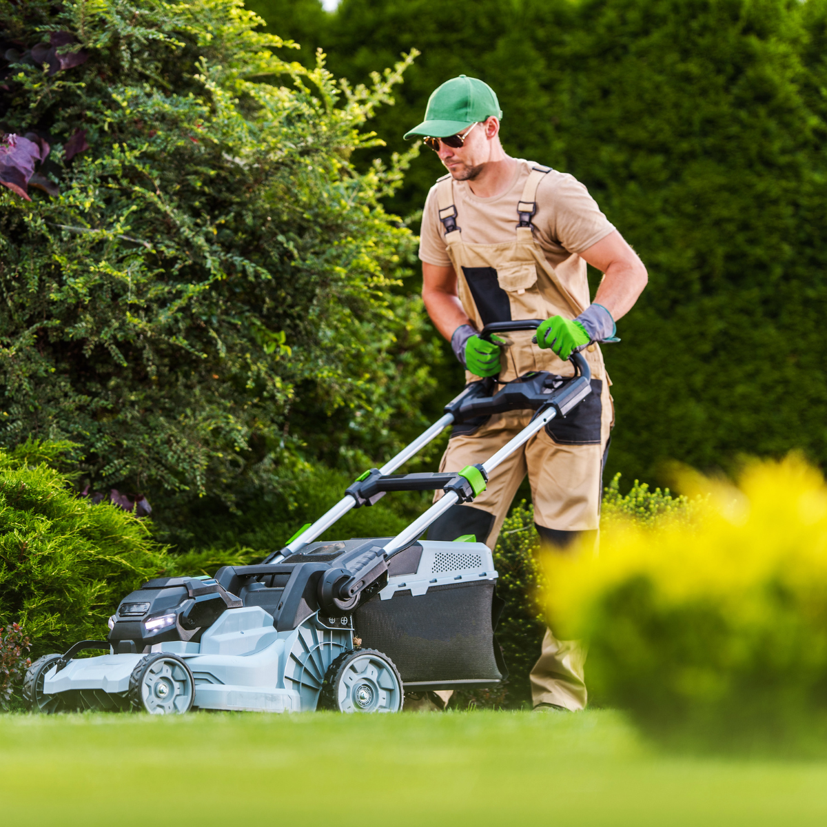 A man is mowing a lush green lawn with a lawn mower.