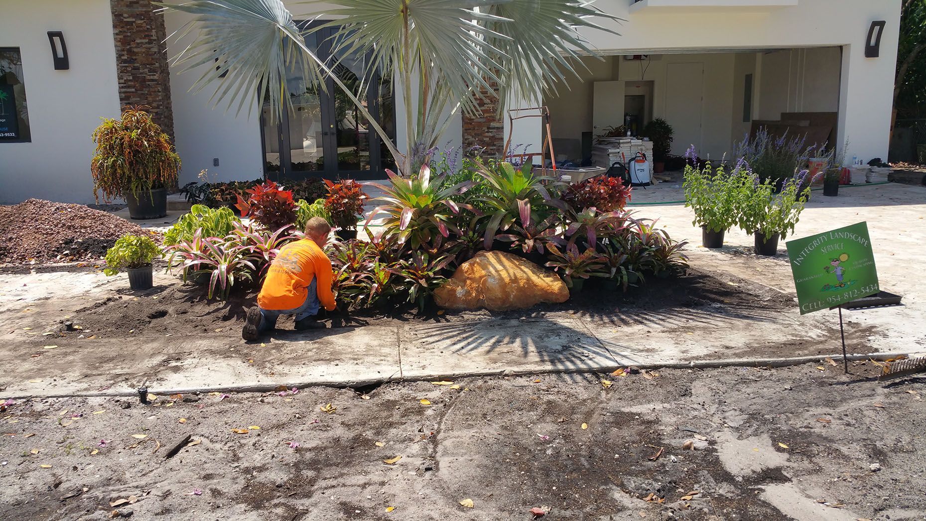 A man is working on a garden in front of a house.