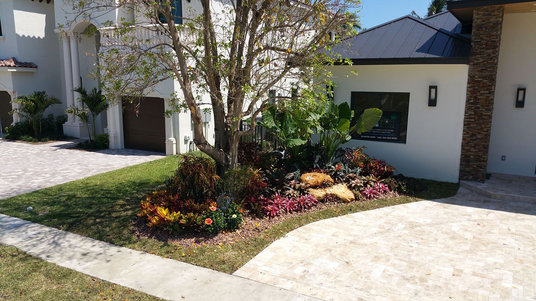 A white house with a driveway and a garden in front of it