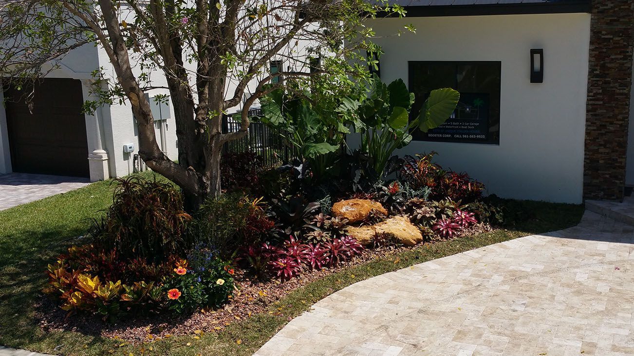 A white house with a driveway and a garden in front of it.