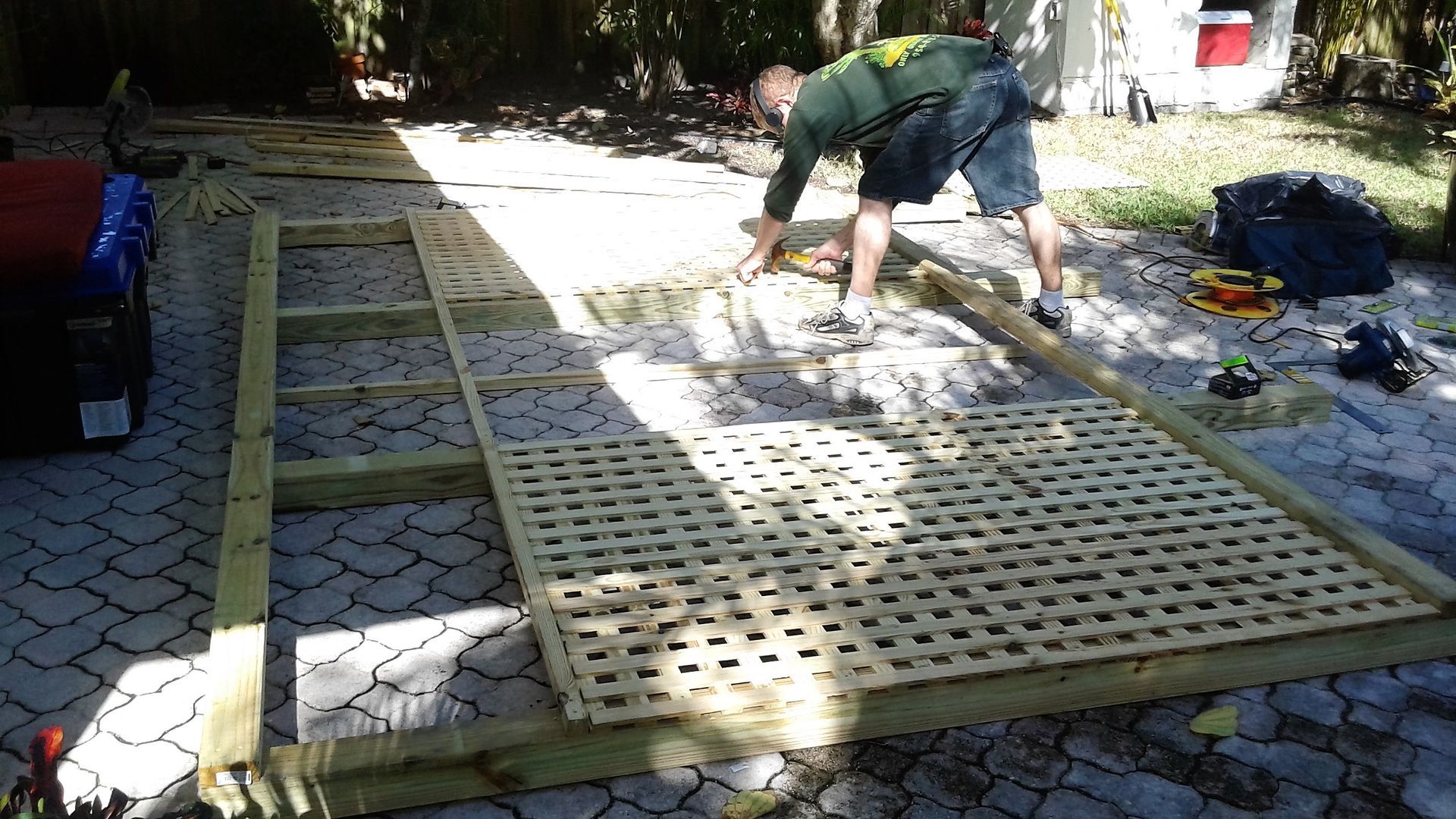 A man is working on a wooden structure in a driveway