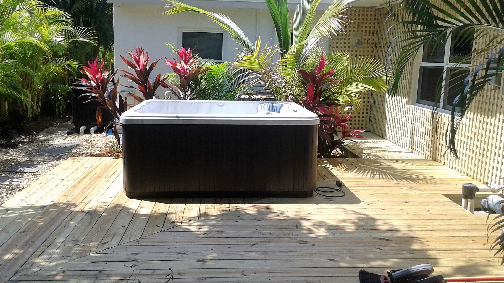 A hot tub is sitting on a wooden deck in front of a house