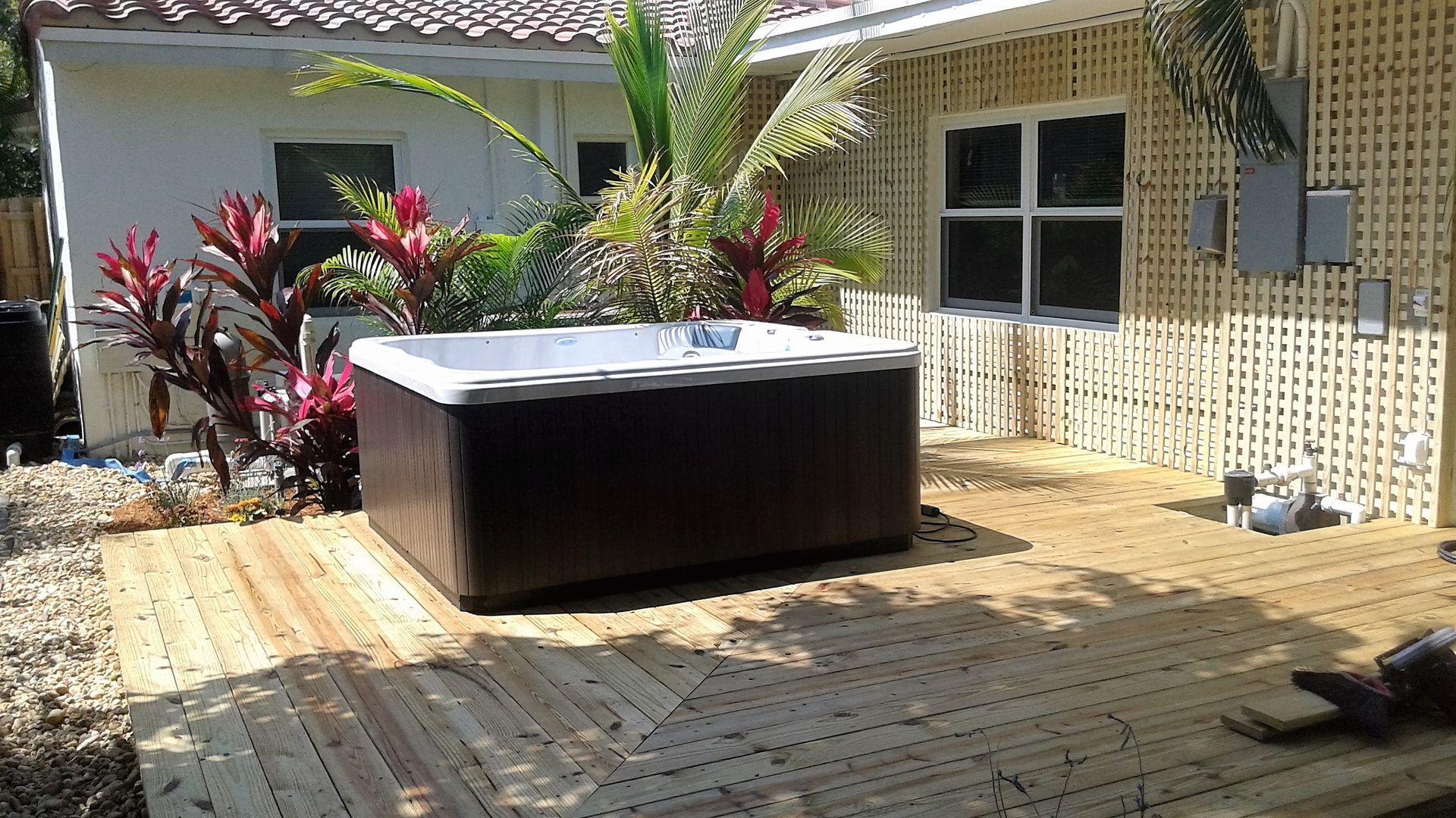 A hot tub is sitting on a wooden deck in front of a house