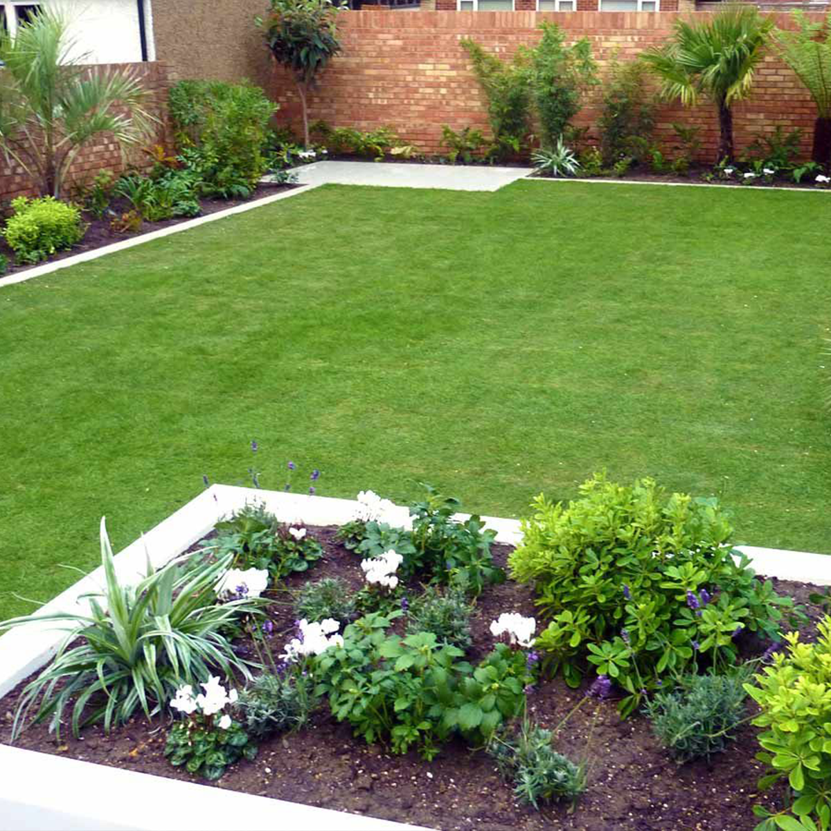A lush green lawn with a brick wall in the background