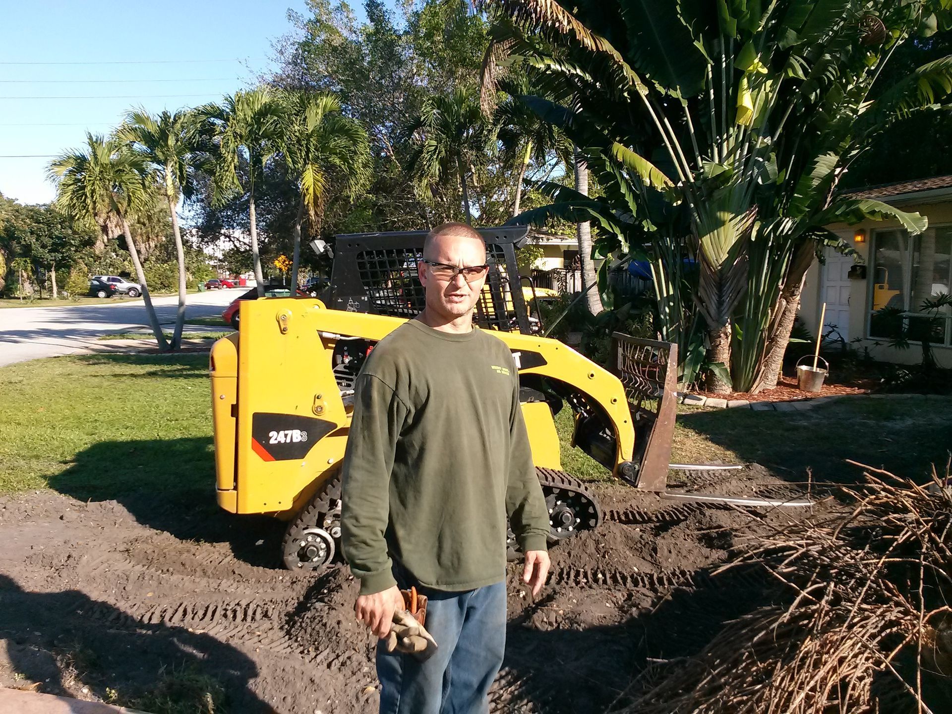 A man in a green shirt is standing in front of a yellow cat machine