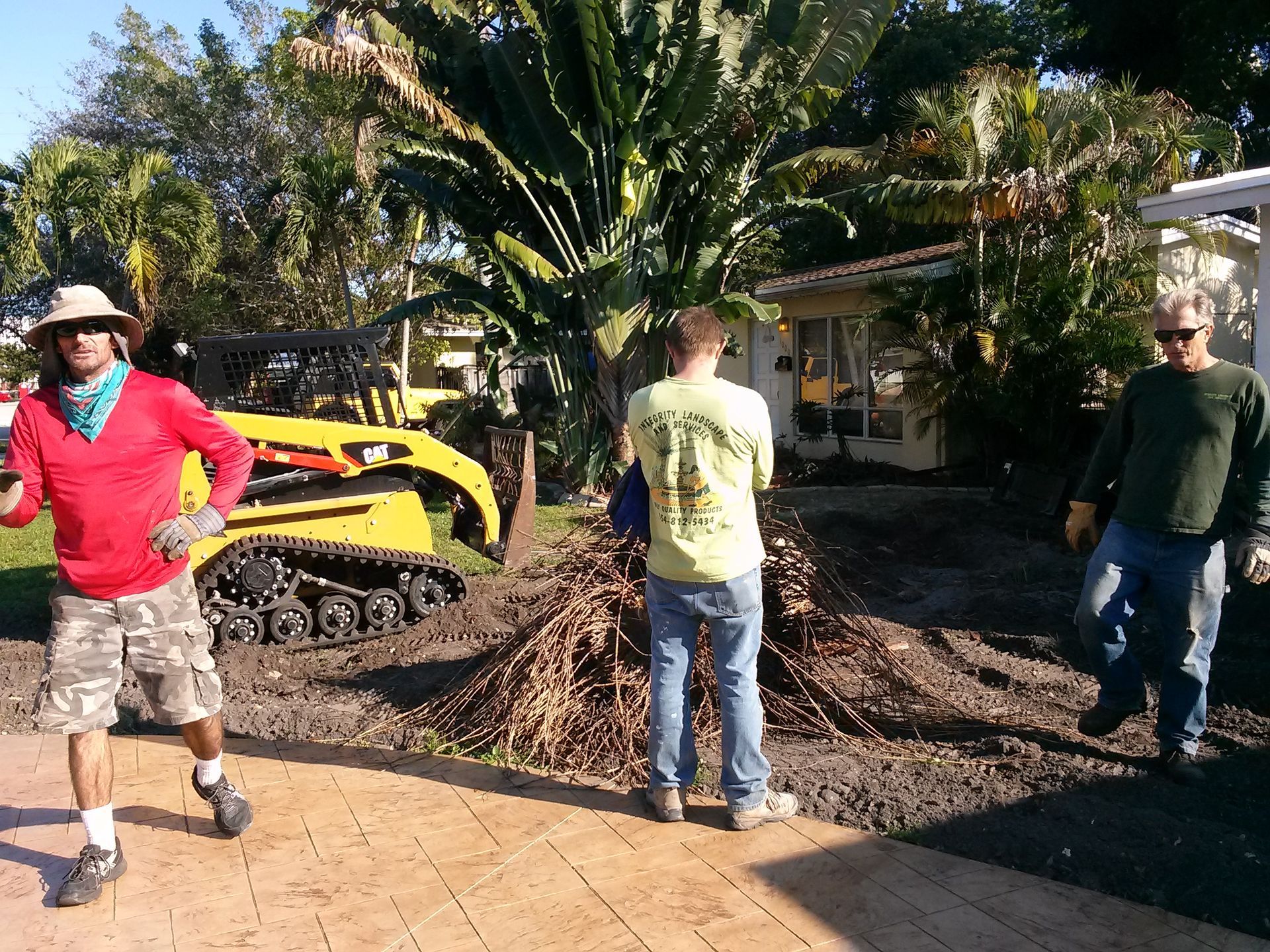 Three men are standing in front of a yellow tractor