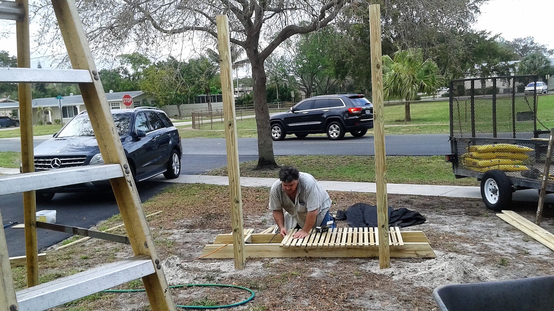 A man is working on a wooden structure in a parking lot.