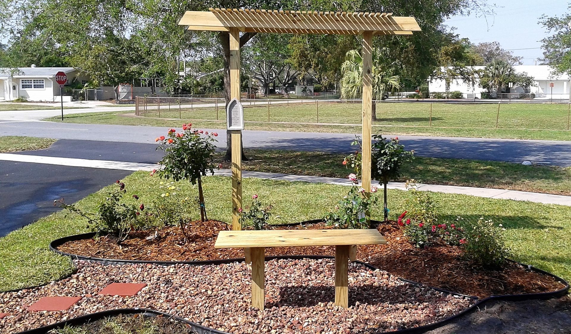 A wooden bench under a pergola in a park