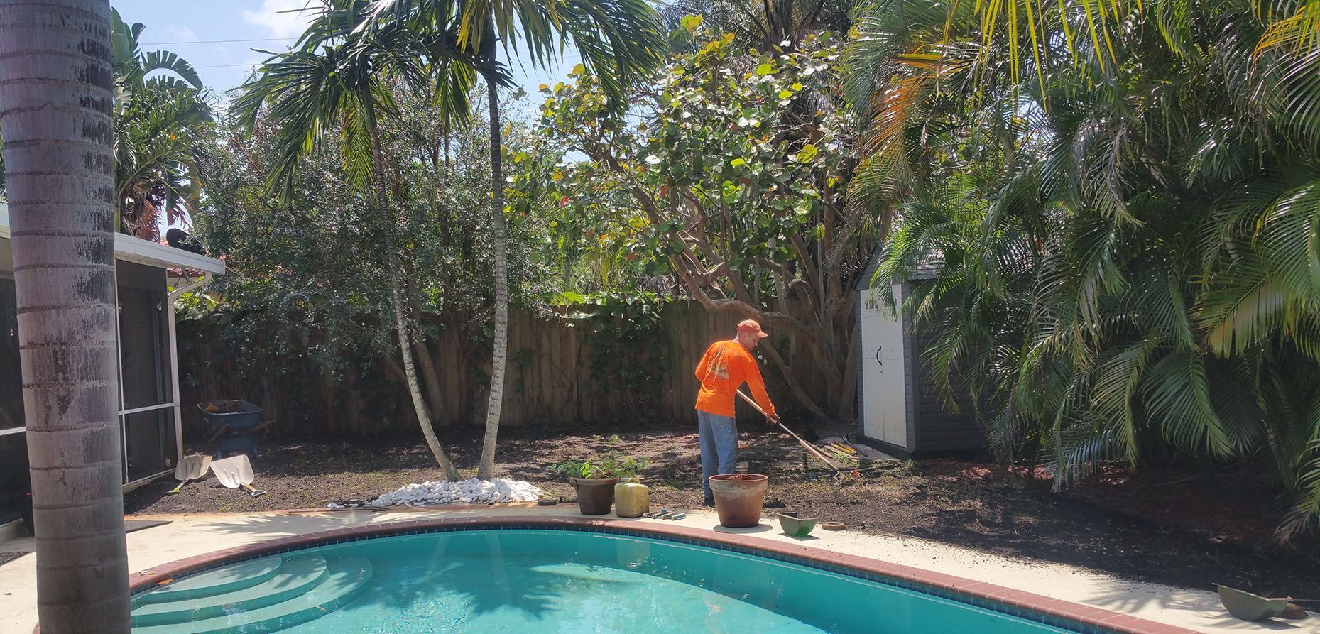 A man is standing next to a swimming pool in a backyard.