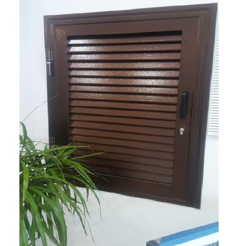 Finestra marrone con persiana, serratura, cerniere e telaio, contro una parete bianca. Pianta verde in primo piano.