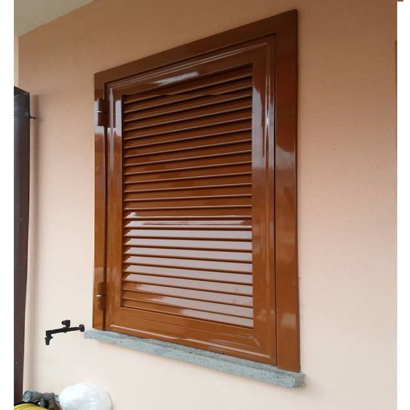 Finestra con persiane marroni su una parete color pesca, con davanzale in pietra.