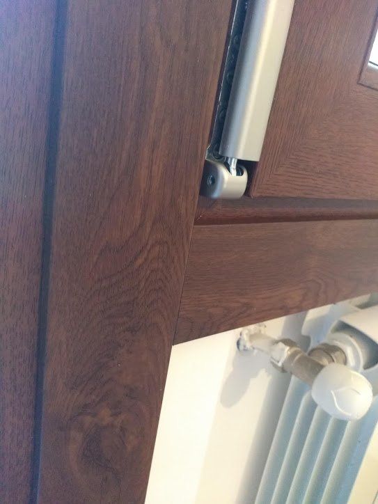 Telaio della finestra in legno marrone con cerniera argentata e termosifone bianco sottostante.