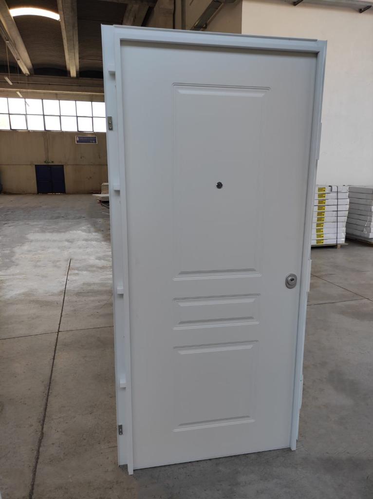 Porta bianca con spioncino e serratura in un magazzino.