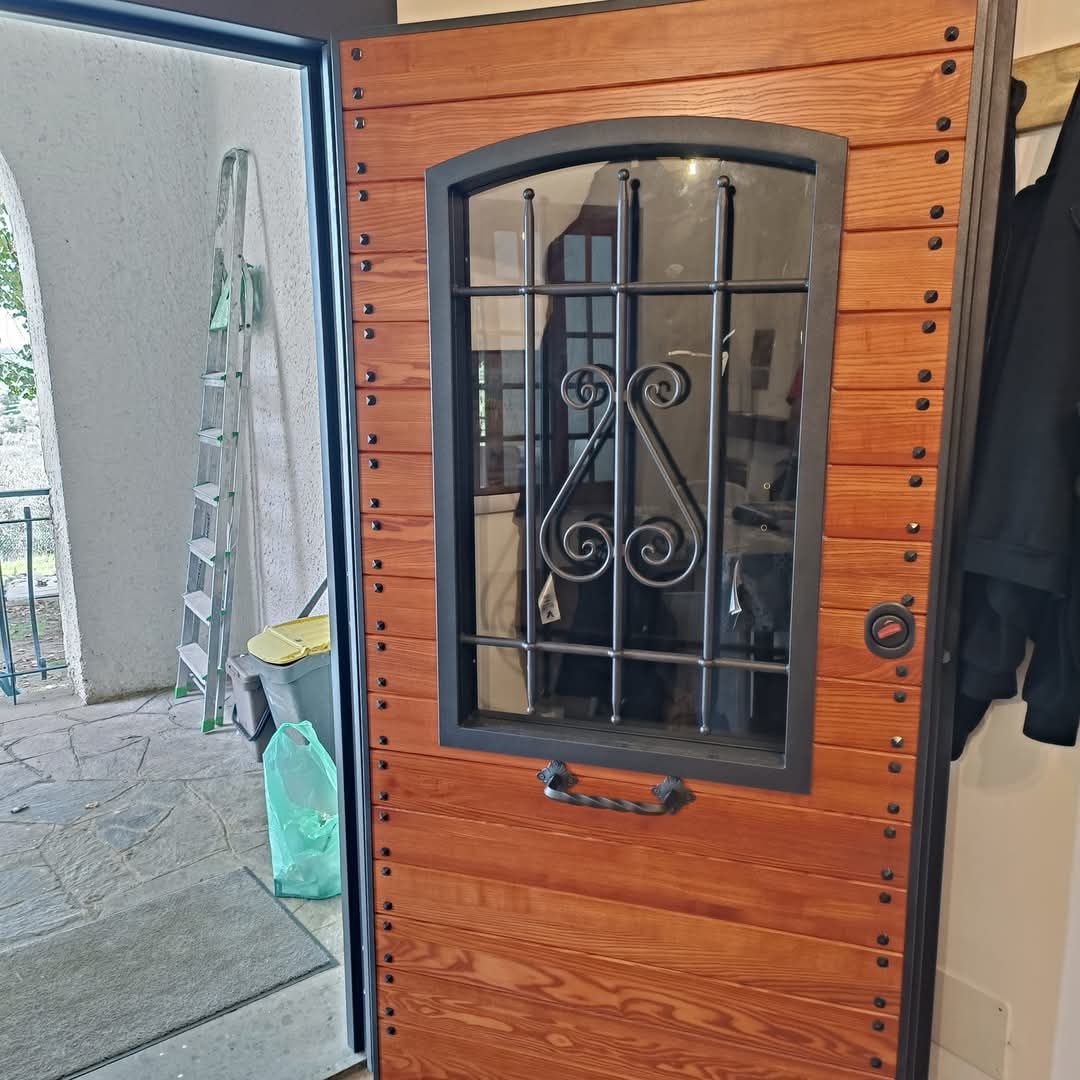 Porta in legno con finestra e maniglia in ferro battuto, che si apre su un ingresso.