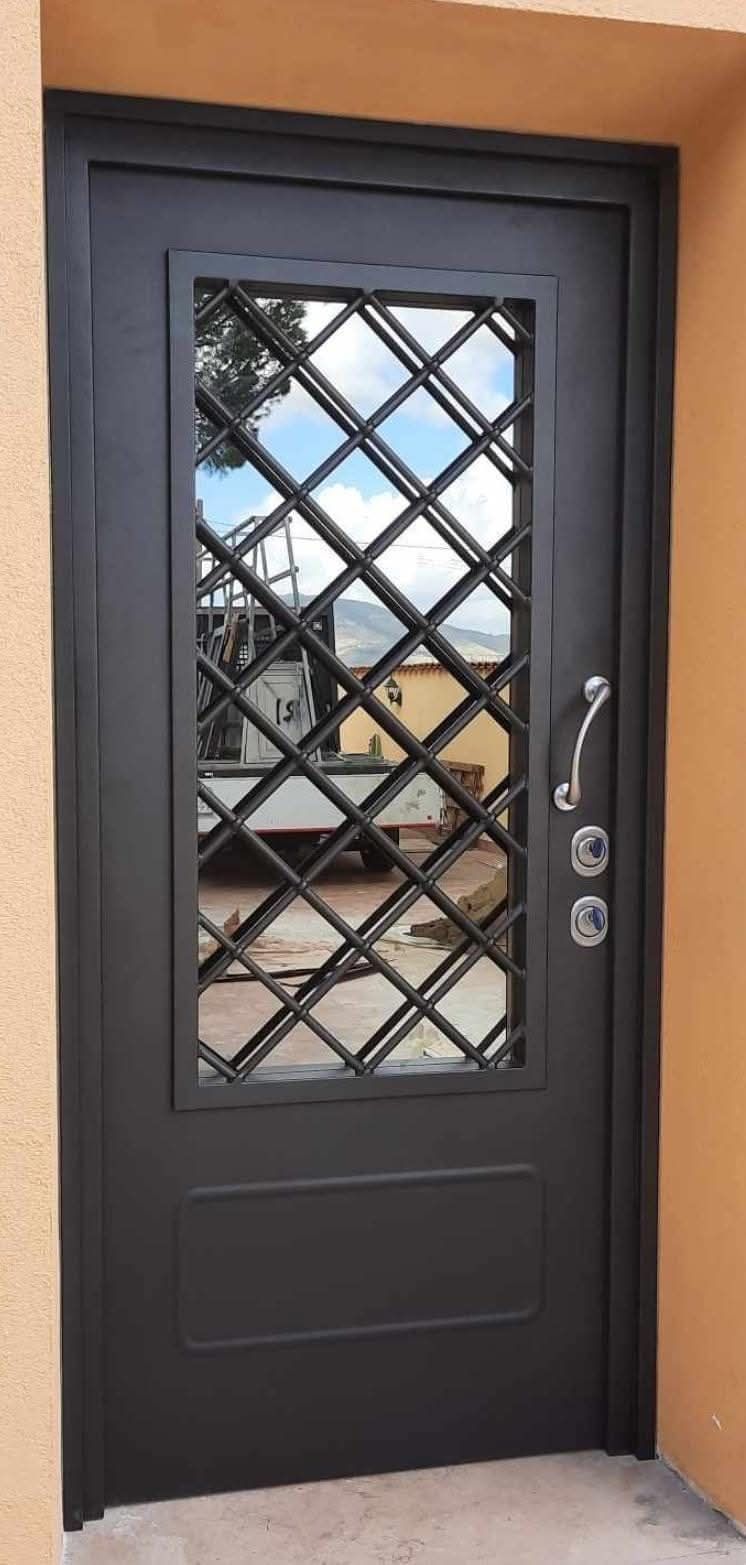 Porta in metallo nero con finestra a rombi. Include maniglia, serrature e pannello rettangolare inferiore.