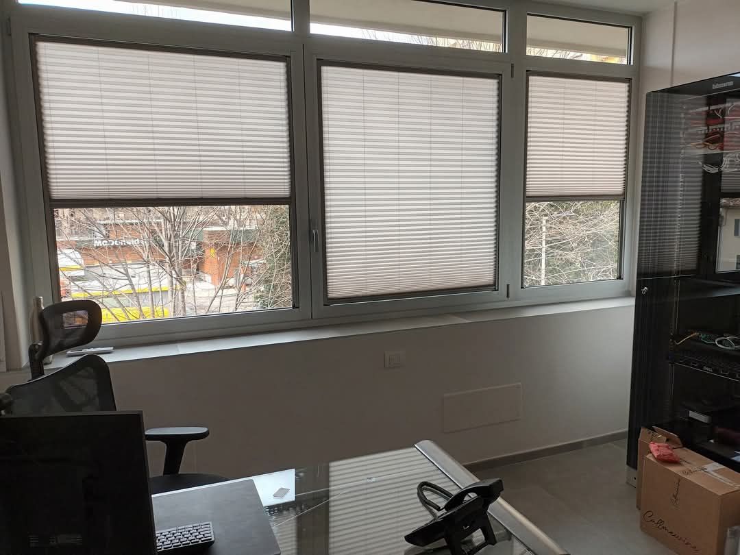 Uno spazio ufficio ben illuminato con tende chiuse. Le finestre si affacciano sull'esterno. 